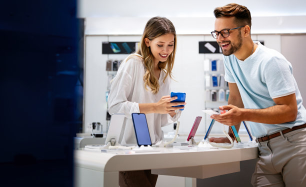 快乐的年轻人在商店里买新手机。人科技设备新概念图片下载