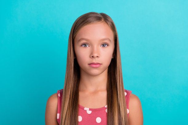 可爱漂亮的小女孩穿粉红色的裙子微笑的照片，孤立的蓝绿色背景图片下载