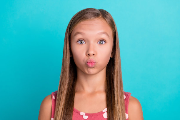 闪亮有趣的小女孩穿粉红色裙子送你吻孤立的蓝绿色背景照片图片下载