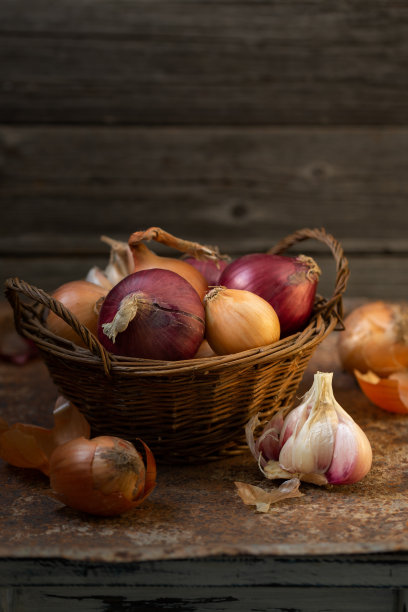 洋葱和大蒜放在旧背景的柳条篮子里。乡村,复古风格图片下载