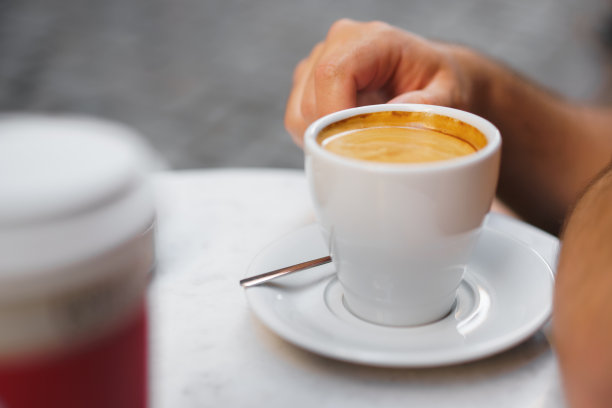 特写照片手拿一杯咖啡在街头咖啡馆图片下载