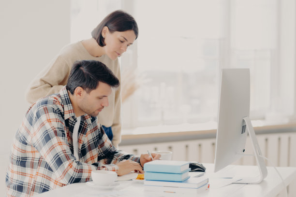 夫妻俩一起写报告，查信息，坐在电脑前，喝咖啡，穿着便装，进行团队合作。家庭和远程工作理念图片下载