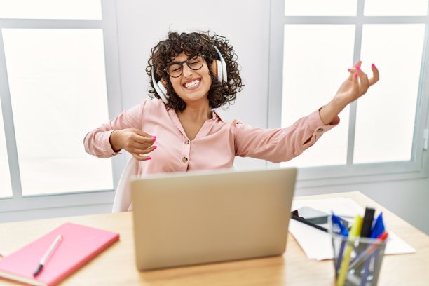 年轻的中东女商人在办公室听音乐。图片下载