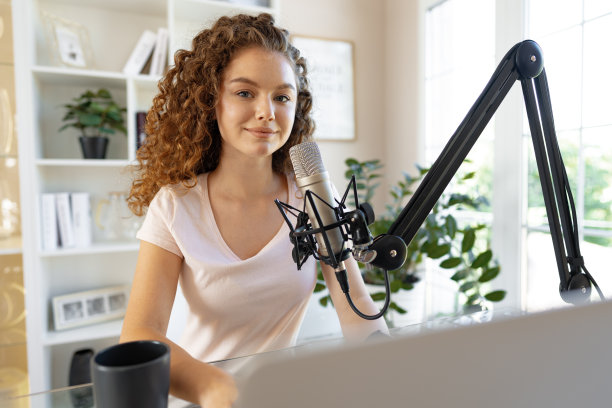 女视频博主看着笔记本电脑，用麦克风录制视频图片下载