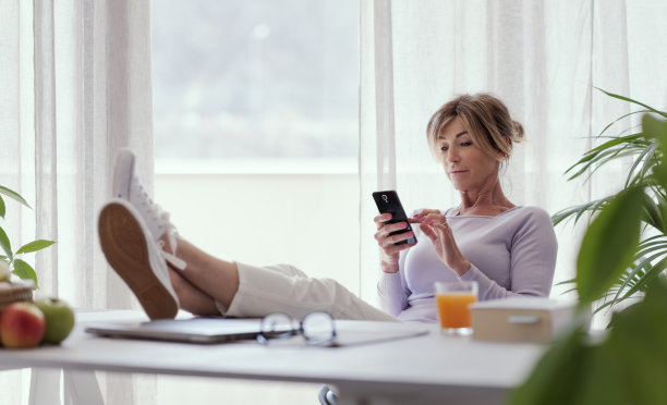 成熟的女人放松和使用她的智能手机图片下载