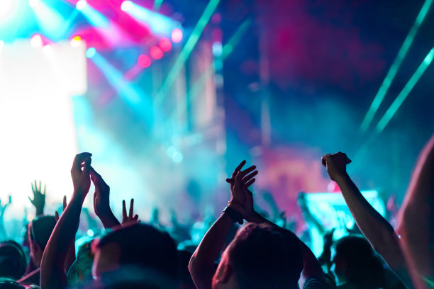 蓝色/蓝绿色/紫色的舞台灯光前，手的海洋。图片下载