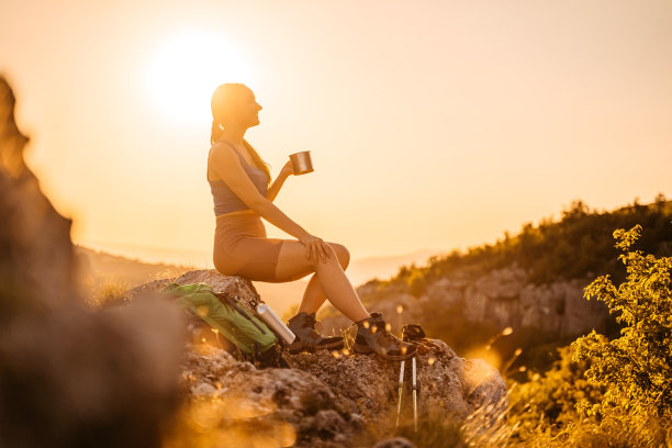 徒步旅行后在山上喝咖啡的年轻女子图片下载