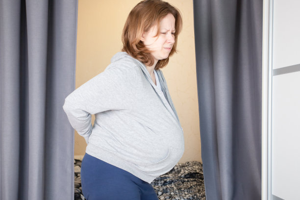 孕妇背痛，骨软骨症，怀孕期间脊柱负重，妇女用手撑住后背图片下载