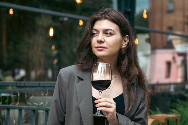 一名年轻女子拿着一杯酒在餐厅外。图片下载