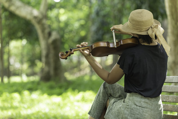 美丽的亚洲女人在自然的背景上拿着小提琴，在情感上幸福的感觉。图片下载