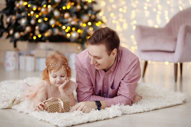 爸爸和女儿在圣诞树旁拥抱。图片下载