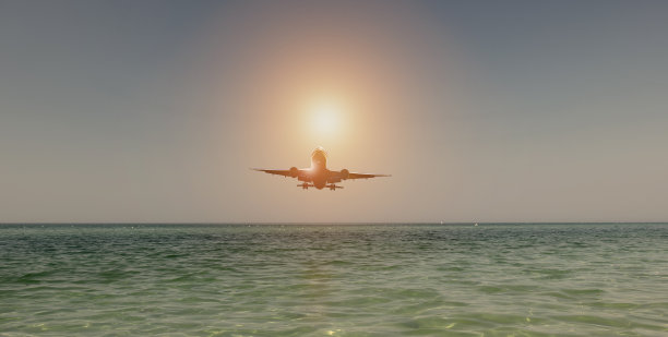 飞机在日落时飞越海面。客机图片下载