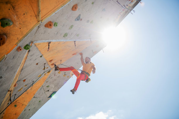 运动员在陡峭的岩石上攀爬，在人造墙上攀爬。图片下载
