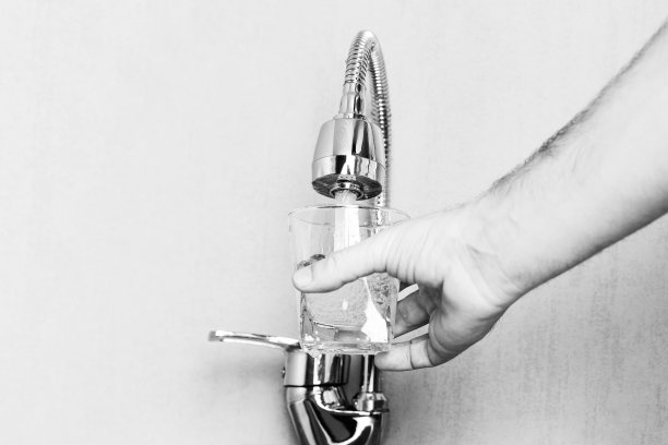 一名男子的手与一个玻璃倒水从水龙头与拷贝空间的黑白照片图片下载