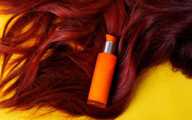 橙色瓶子和红色头发的护发产品图片下载