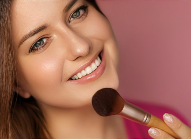 美丽的年轻女子应用化妆品粉产品与化妆竹刷，美容，化妆和护肤化妆品模型的脸肖像在粉红色的背景图片下载