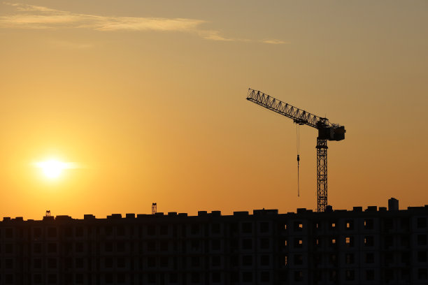 塔吊的剪影和未完工的建筑晨光背景图片下载