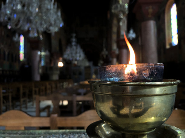 在一个古老的黑暗的教堂里靠近蜡烛的火焰图片下载