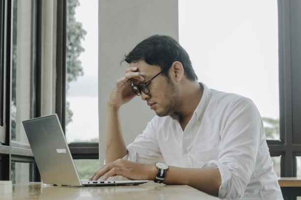 沮丧绝望的商人坐在家里的办公桌前，看起来很沮丧。图片下载