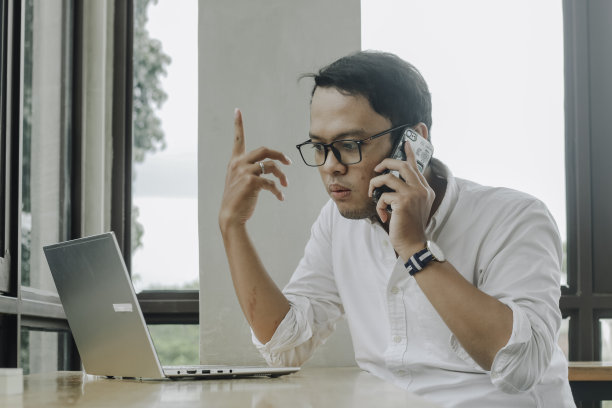 年轻的亚洲商人在咖啡馆的办公桌前用智能手机聊天图片下载