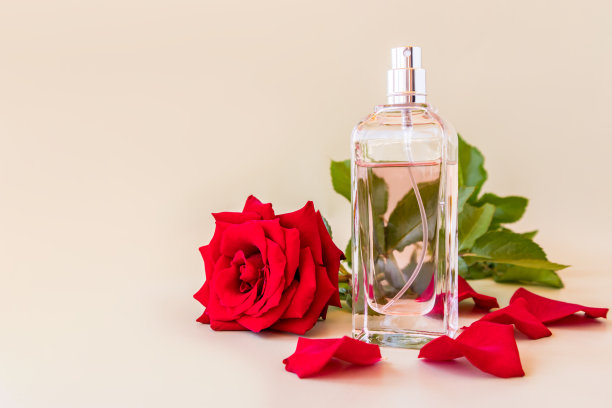 美丽的瓶子的女性香水在一个柔和的背景与别致的花芳香的红玫瑰。前视图。香水的模板。一份空间。图片下载