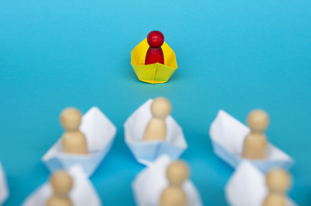 领导理念——红色木图在黄色纸船上折纸领导其余的人在白色纸船上。副本的空间。图片下载