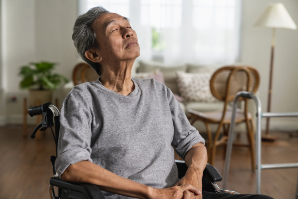 一名老人坐在轮椅上望向窗外的照片，一名亚洲老人独自坐在轮椅上从客厅望向窗外的景色图片下载