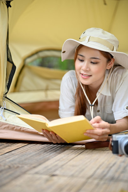 美丽的年轻亚洲女性放松阅读一本书，而冷却和躺在她的帐篷图片下载