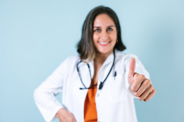 拉丁女医生指着蓝色背景的拷贝空间笑在墨西哥拉丁美洲图片下载