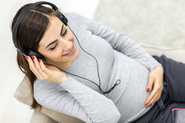 孕妇戴耳机的俯视图照片。图片下载