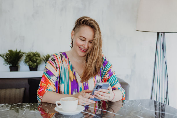 美丽的年轻女子坐在家里，浏览图片的智能手机，专注于设备屏幕图片下载