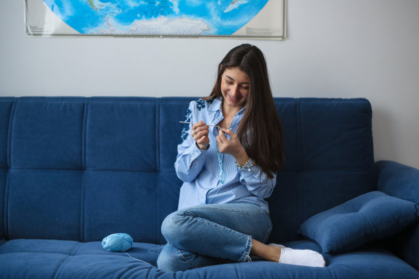 迷人的女人在蓝色的沙发上从事创意图片下载