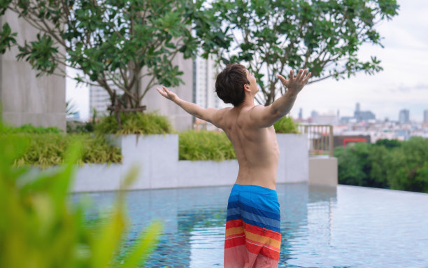 年轻人抬起头，吸了一口气，张开双臂，享受自由和生活，假期快乐。图片下载