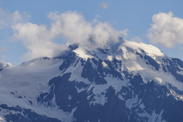 美丽的雪山覆盖在雾和戏剧性的云。图片下载