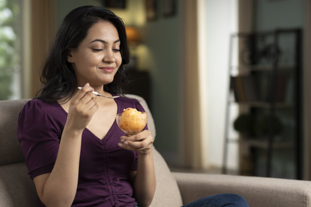 一个年轻女人在家里吃冰淇淋的肖像股票照片图片下载