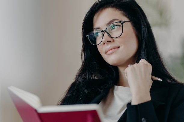 沉思的女企业主在计划日程表上工作，在笔记本上写字，拿着笔，看起来若有所思，穿着正式的衣服和眼镜，思考创意，集中在一边图片下载