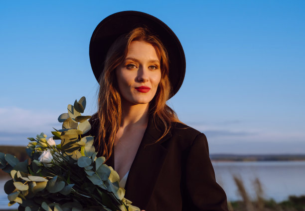 戴帽子的时髦女人。在日落大道上摆姿势的女孩。图片下载