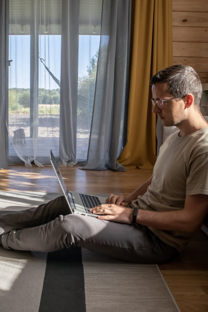 舒适的在家工作。一个男人坐在地板上工作图片下载
