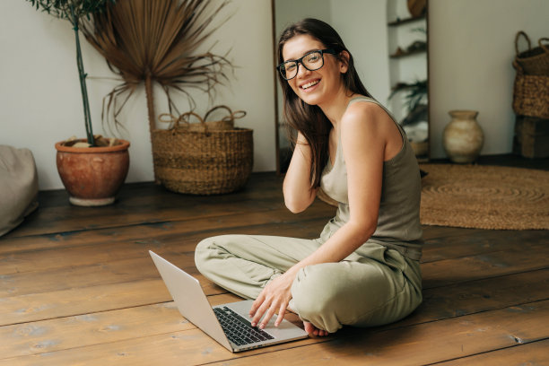 年轻的黑人女孩坐在地板上用笔记本电脑工作。图片下载