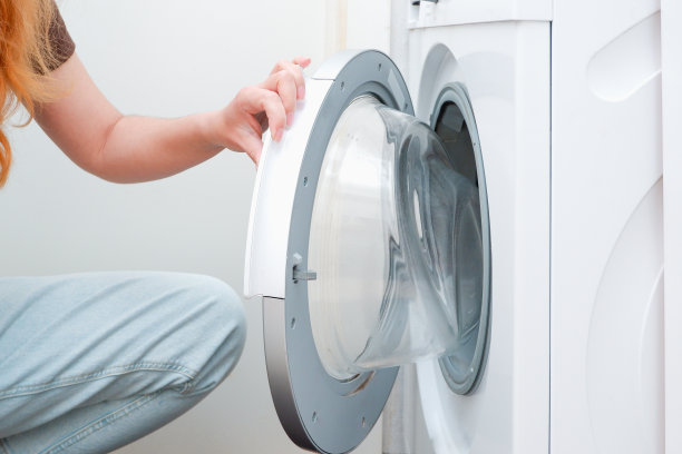 洗衣服。一个女人正在给洗衣机装东西。光内部。特写镜头。图片下载