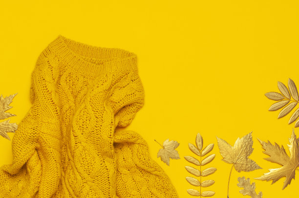 秋平铺构图。橘黄色针织羊毛女毛衣和金色叶在黄色背景俯视图。时尚女性秋季配饰。舒适的针织套头衫时髦的女士衣服图片下载