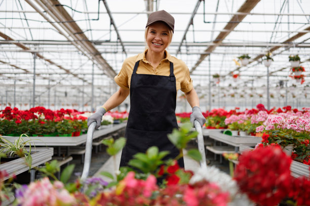 一个女人推着手推车在温室里放着花的肖像图片下载