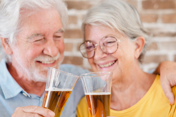 分散的高级微笑夫妇举杯与一杯金发啤酒图片下载