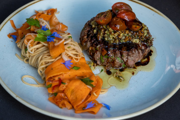 烤牛排与意大利面，番茄和胡萝卜在盘子孤立在黑色的背景图片下载