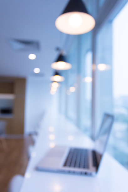 笔记本电脑在新建的现代化办公大楼，公司的商务桌靠近玻璃窗户图片下载