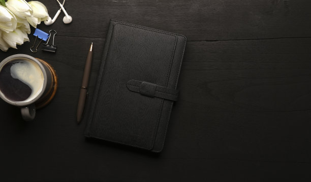 黑色木桌上放着笔记本、耳机和咖啡杯。俯视图，剥皮lay，复制空间。图片下载