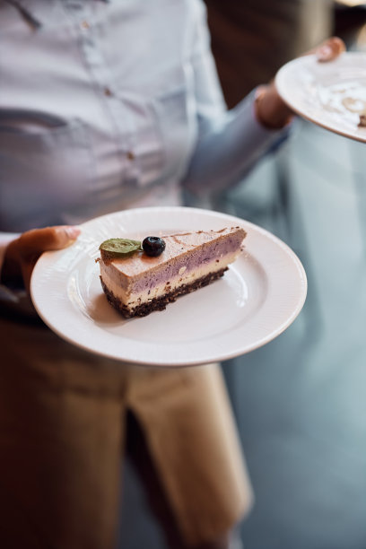 咖啡馆服务员端起芝士蛋糕的特写。图片下载