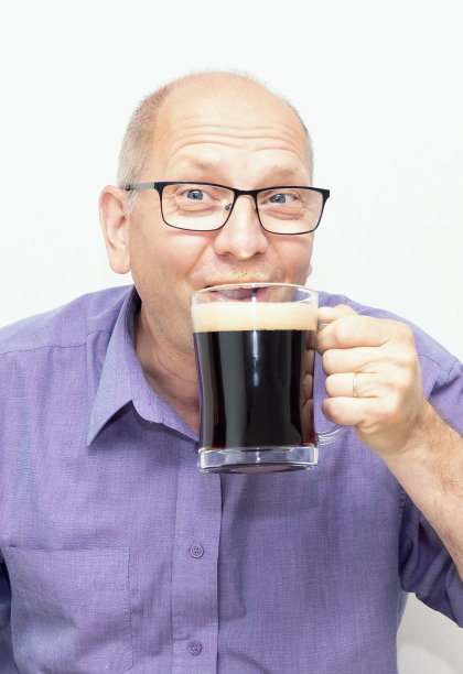 一名50岁的白人男子高兴地喝着黑啤酒。图片下载