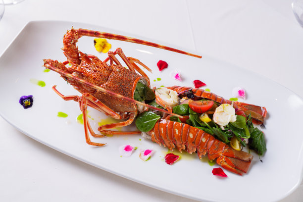 龙虾放在盘子里，切成两半，里面放上菠菜和蔬菜图片下载