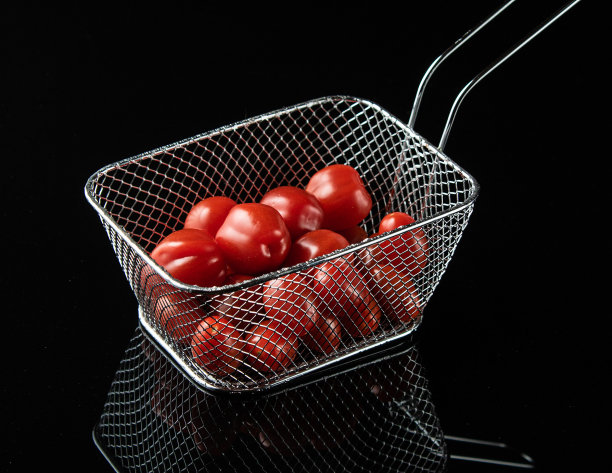 黑色玻璃背景的金属篮子里放着西红柿图片下载
